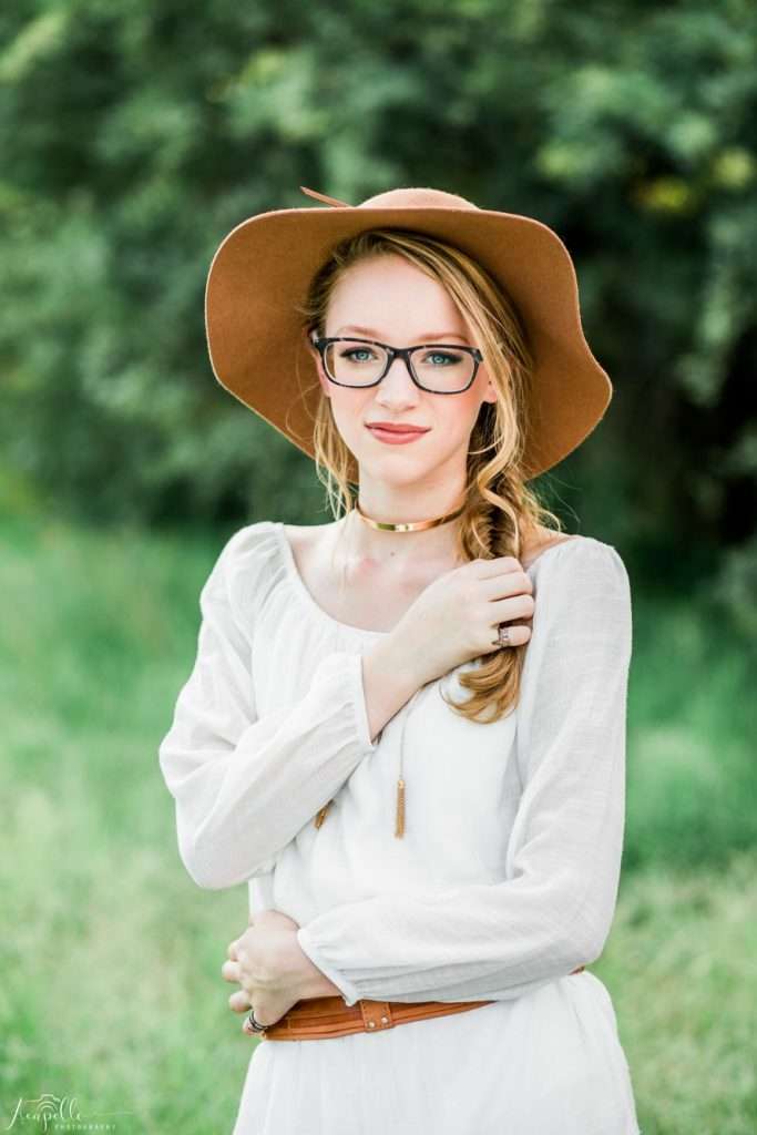 A woman wearing a hat and glasses standing in a field captured by a Phoenix Arizona photographer.