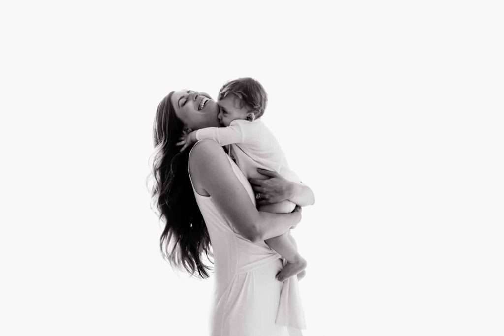 A woman is holding a baby in her arms during a cake smash.