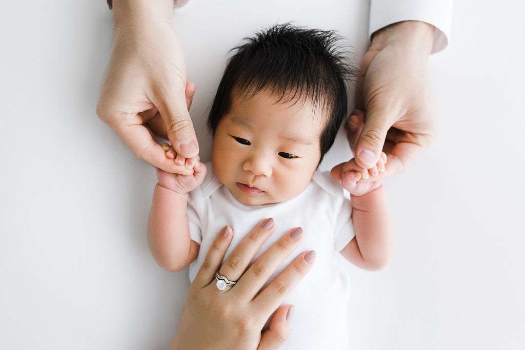A newborn is being held by someone's hands in a Phoenix photo studio.