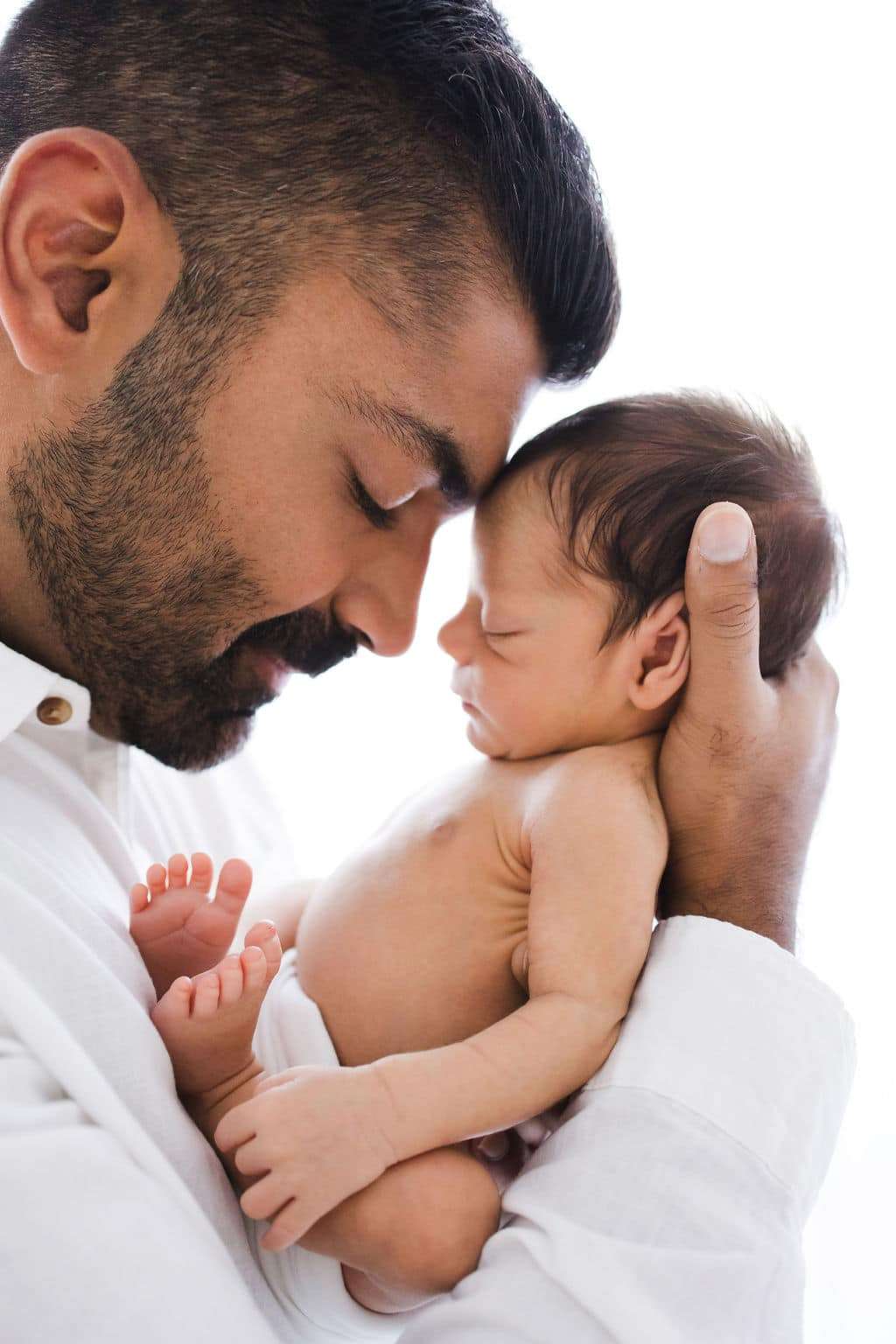 Newborn Photography: A man cradles a newborn baby.