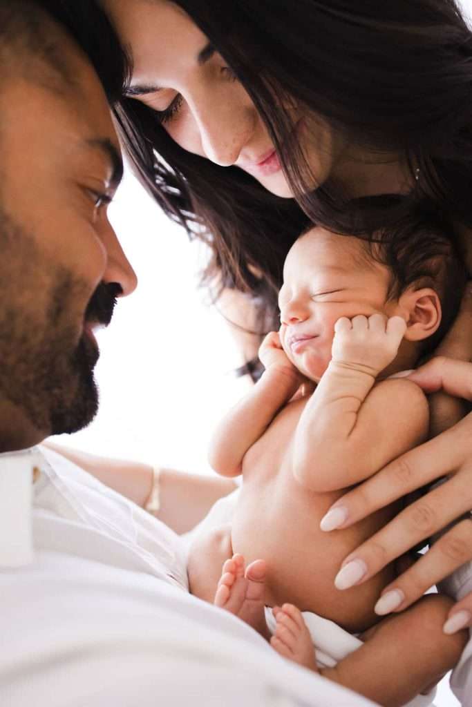 A couple is cradling a newborn baby in their arms.