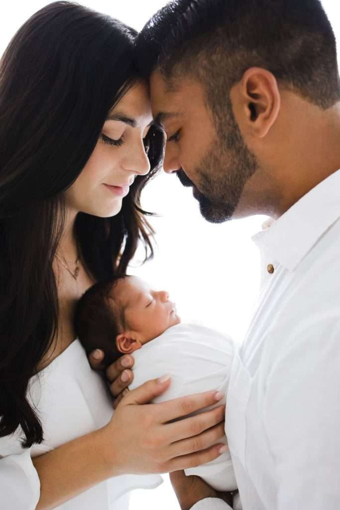 A couple poses with their newborn baby for a newborn photography session.