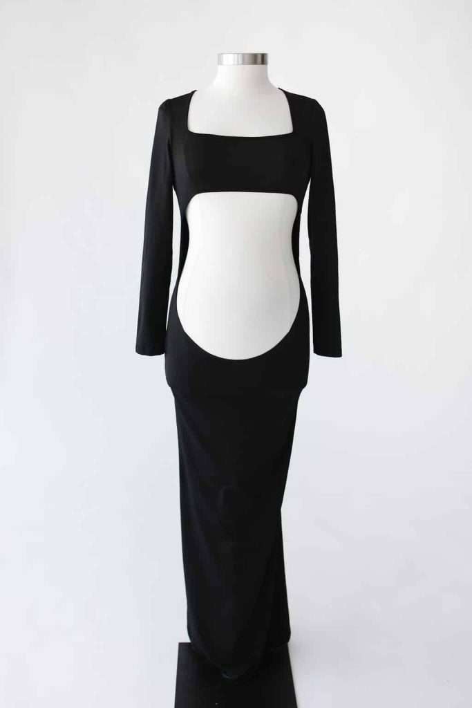 Black long-sleeved floor-length dress on a mannequin with bold cutouts at the waist and midriff, creating a geometric design.