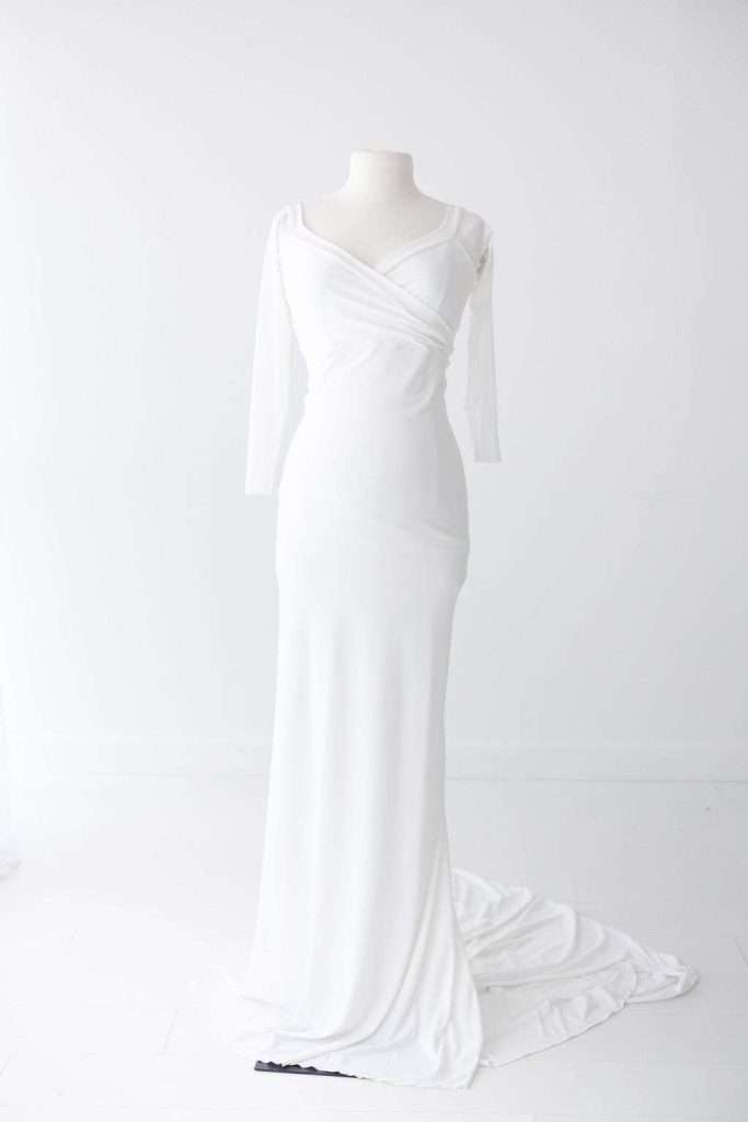 A white long-sleeve floor-length dress with a draped bodice and fitted silhouette displayed on a dress form against a plain white background.