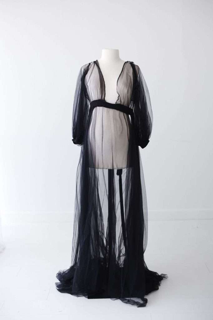 A mannequin displays a sheer black tulle robe with long sleeves and a deep V-neck, set against a plain white background.