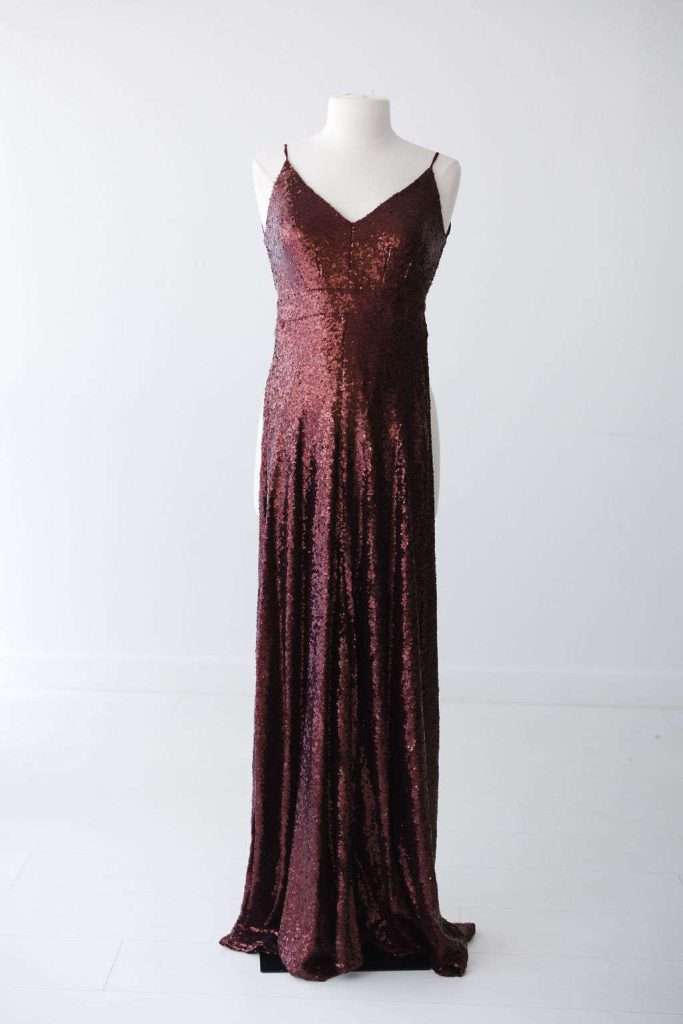 A sleeveless, floor-length gown with thin straps and a V-neckline, covered in dark red sequins, displayed on a dress form against a plain white background.