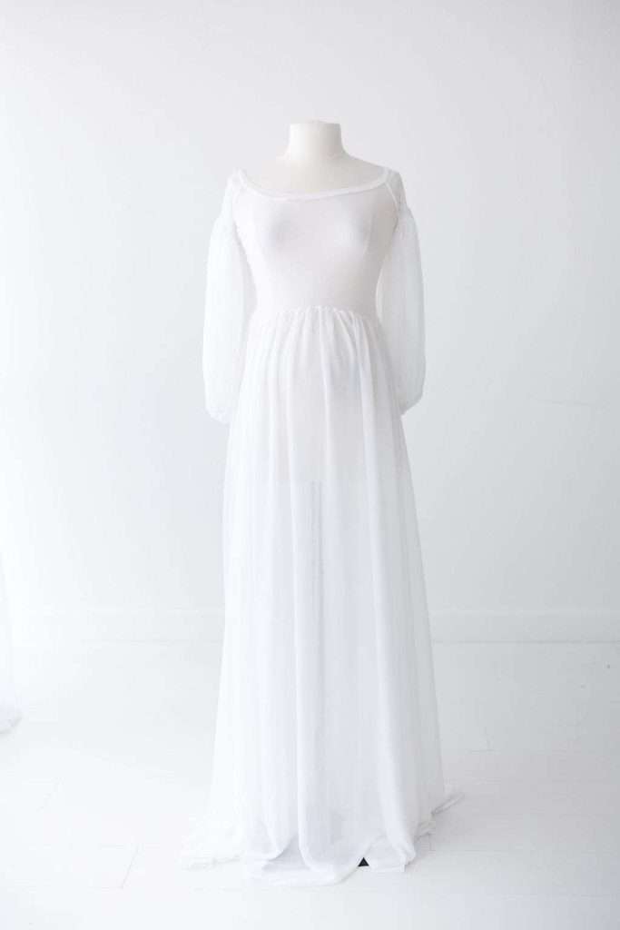 A white, sheer, long-sleeve maternity gown displayed on a headless mannequin against a plain white background.