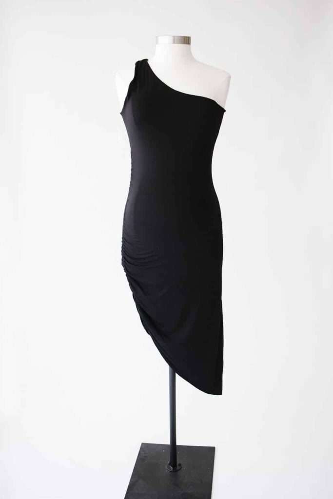 Black one-shoulder, asymmetrical midi dress displayed on a dress form against a plain white background.