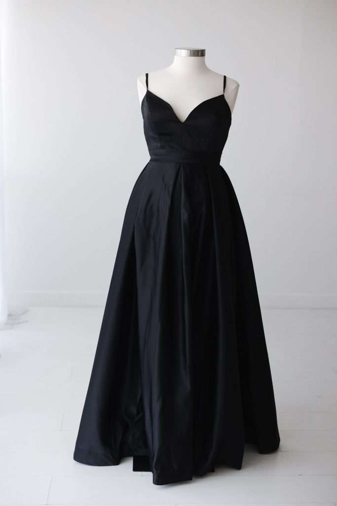 A long, black, sleeveless evening gown with a sweetheart neckline and fitted bodice displayed on a dress form against a plain white background.