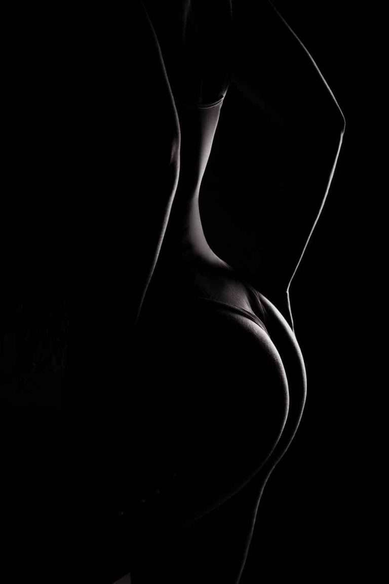 A silhouette of a person in underwear is shown from the back, with dramatic lighting highlighting the contours of their body against a dark background.