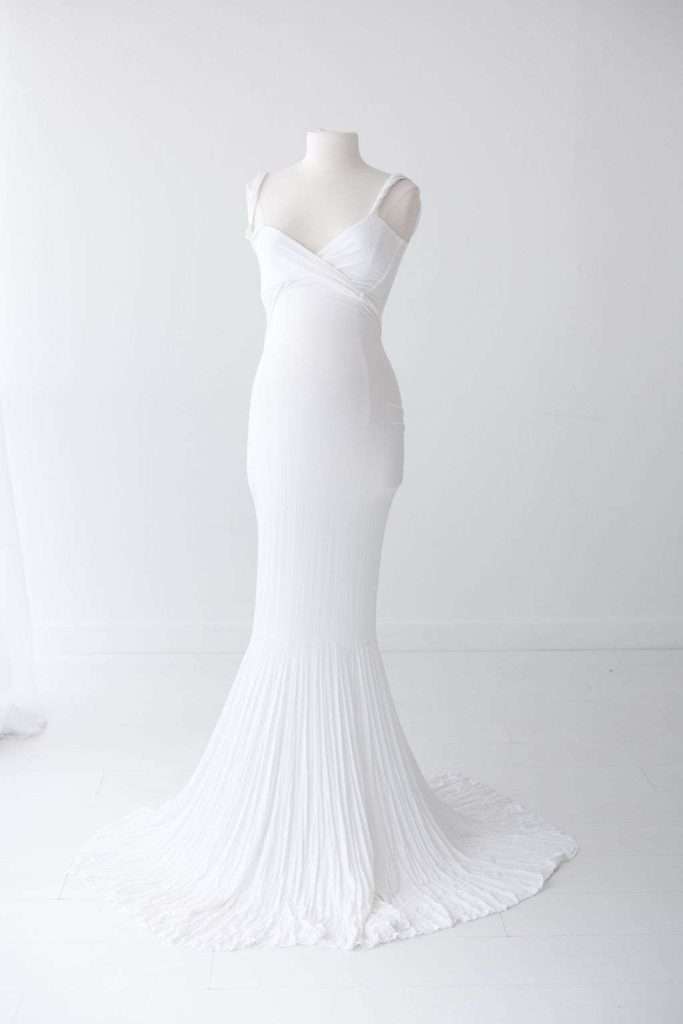 White sleeveless, floor-length gown with a fitted bodice and flared pleated skirt displayed on a mannequin against a plain white background.