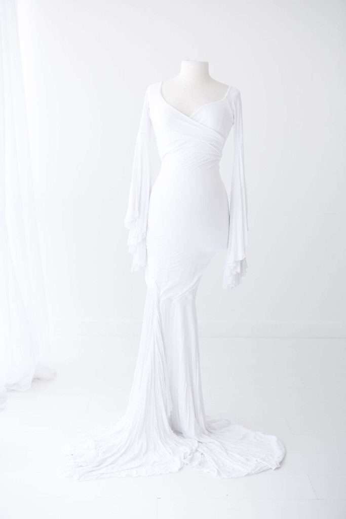White, long-sleeved, floor-length gown with a fitted bodice and flared, flowing sleeves displayed on a mannequin against a plain white background.
