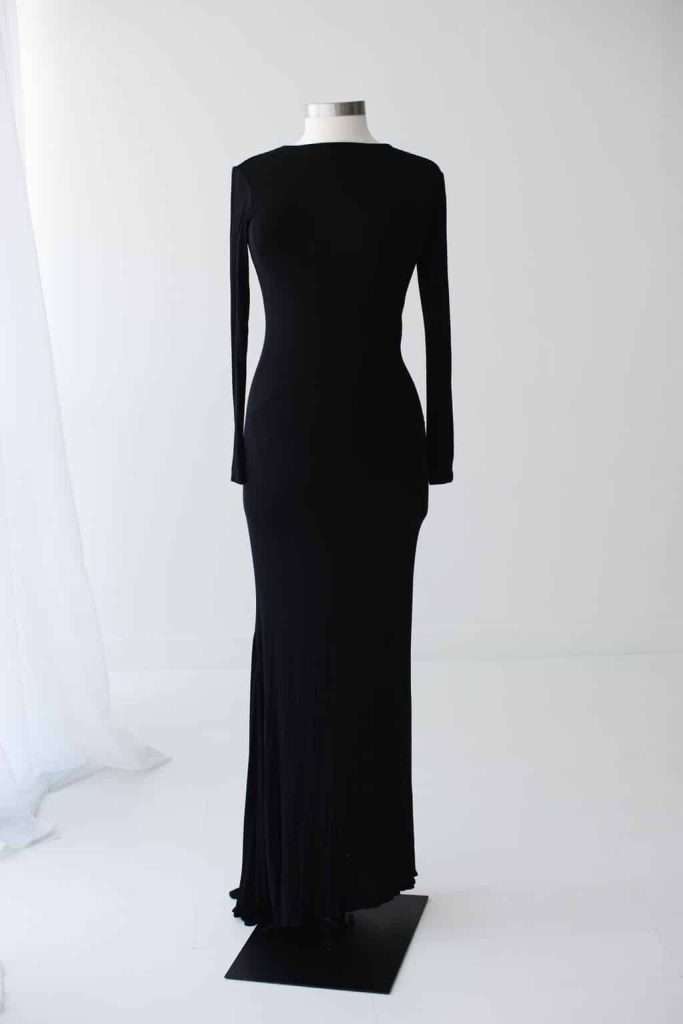 A black, long-sleeved, floor-length dress displayed on a headless mannequin against a white background.