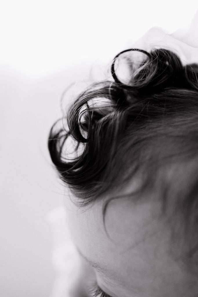 Close-up of a child’s head with soft curls of hair in focus; image is black and white with a blurred background.