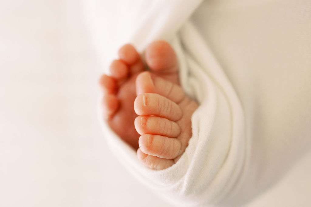 Close-up of a newborn baby's feet wrapped in a soft white blanket.