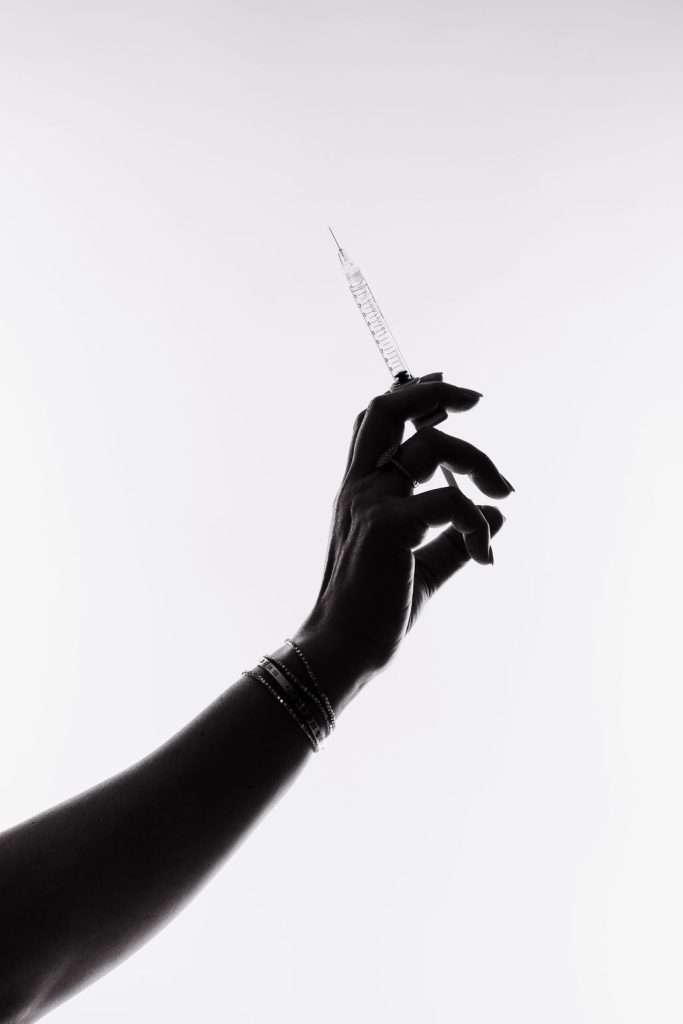 Silhouette of a hand holding a syringe upright against a white background.
